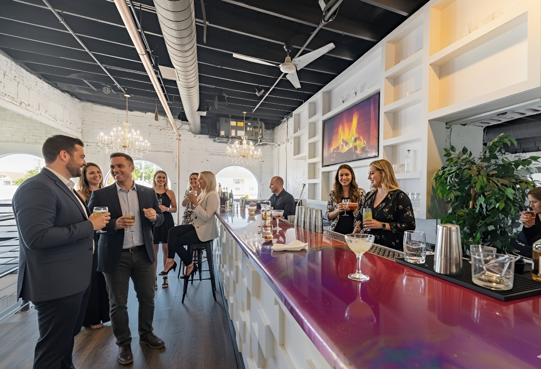 Guests enjoying cocktails at the Mezzanine Bar with its glossy red bar top and chandeliers